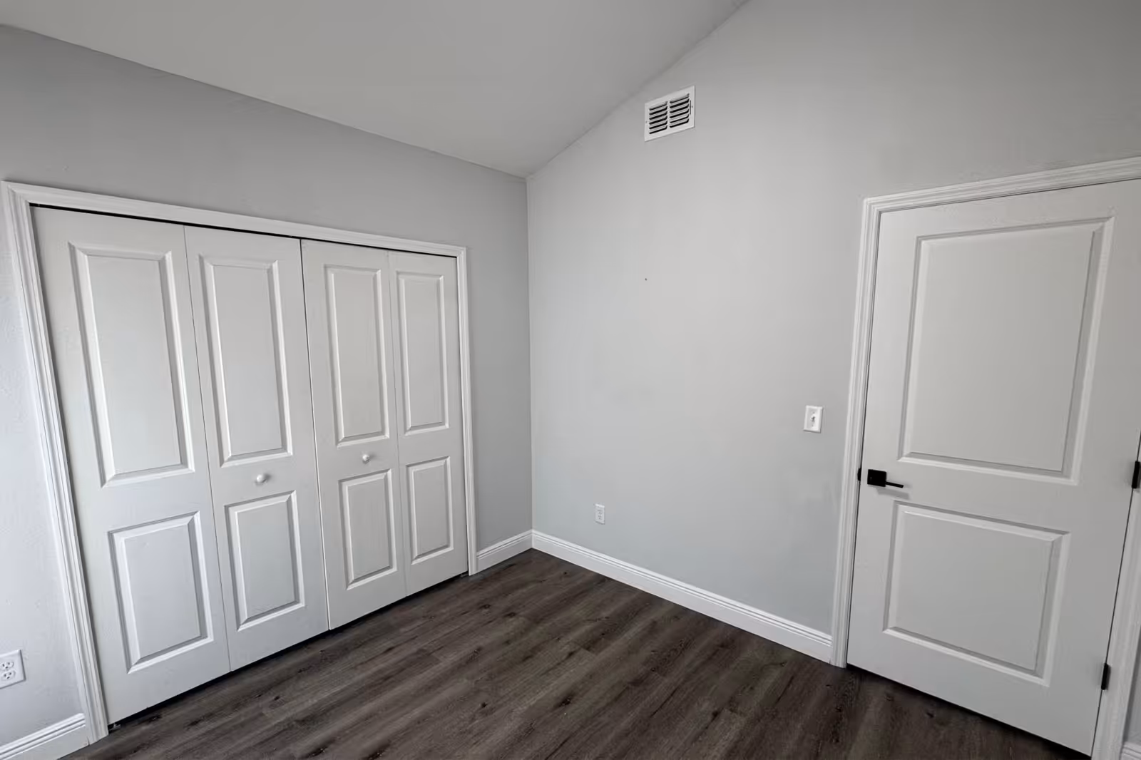 Open floor plan addition with wood panel accent wall and kitchen view